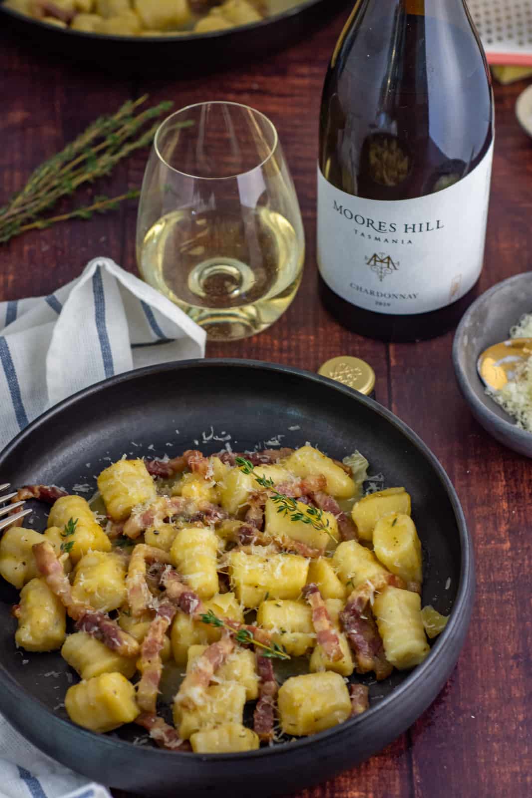 a bowl of gnocchi carbonara and moores hill chardonnay