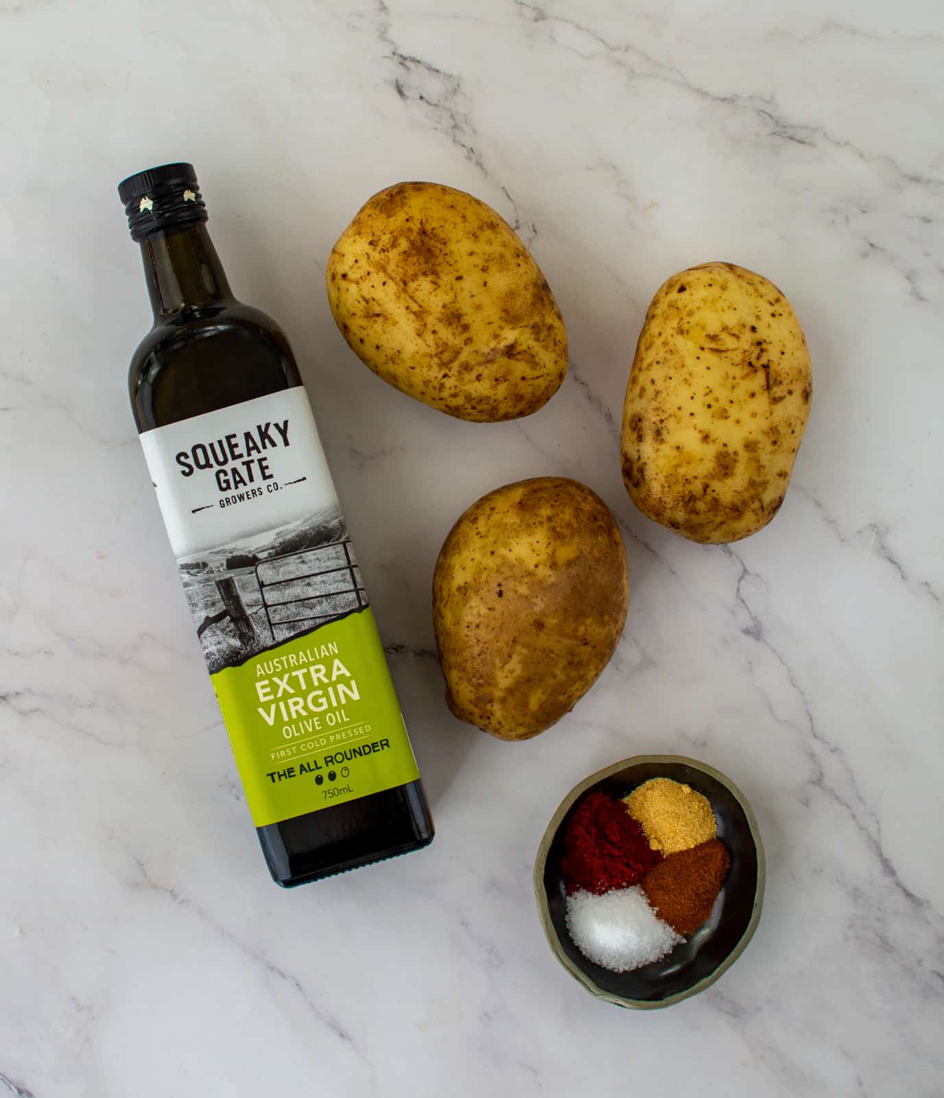 potatoes, olive oil and spices on kitchen counter