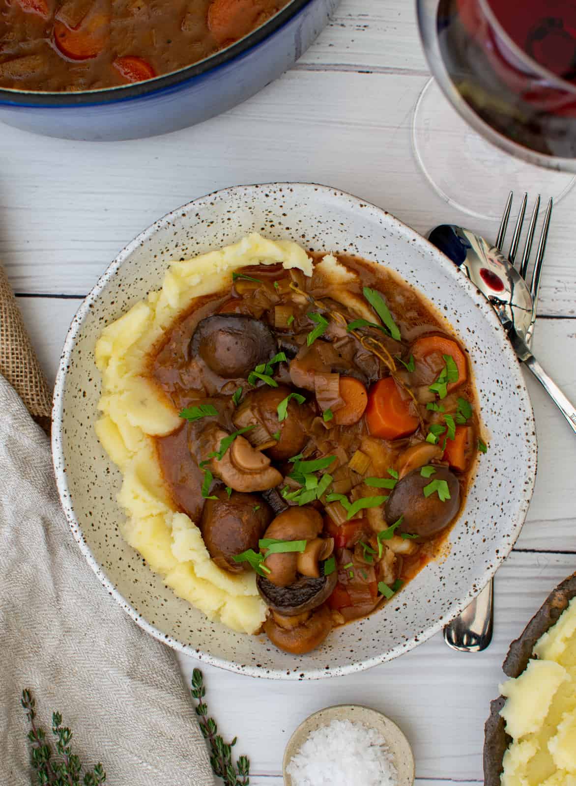 vegetarian stew in a bowl on table with wine and a pot of stew next to it