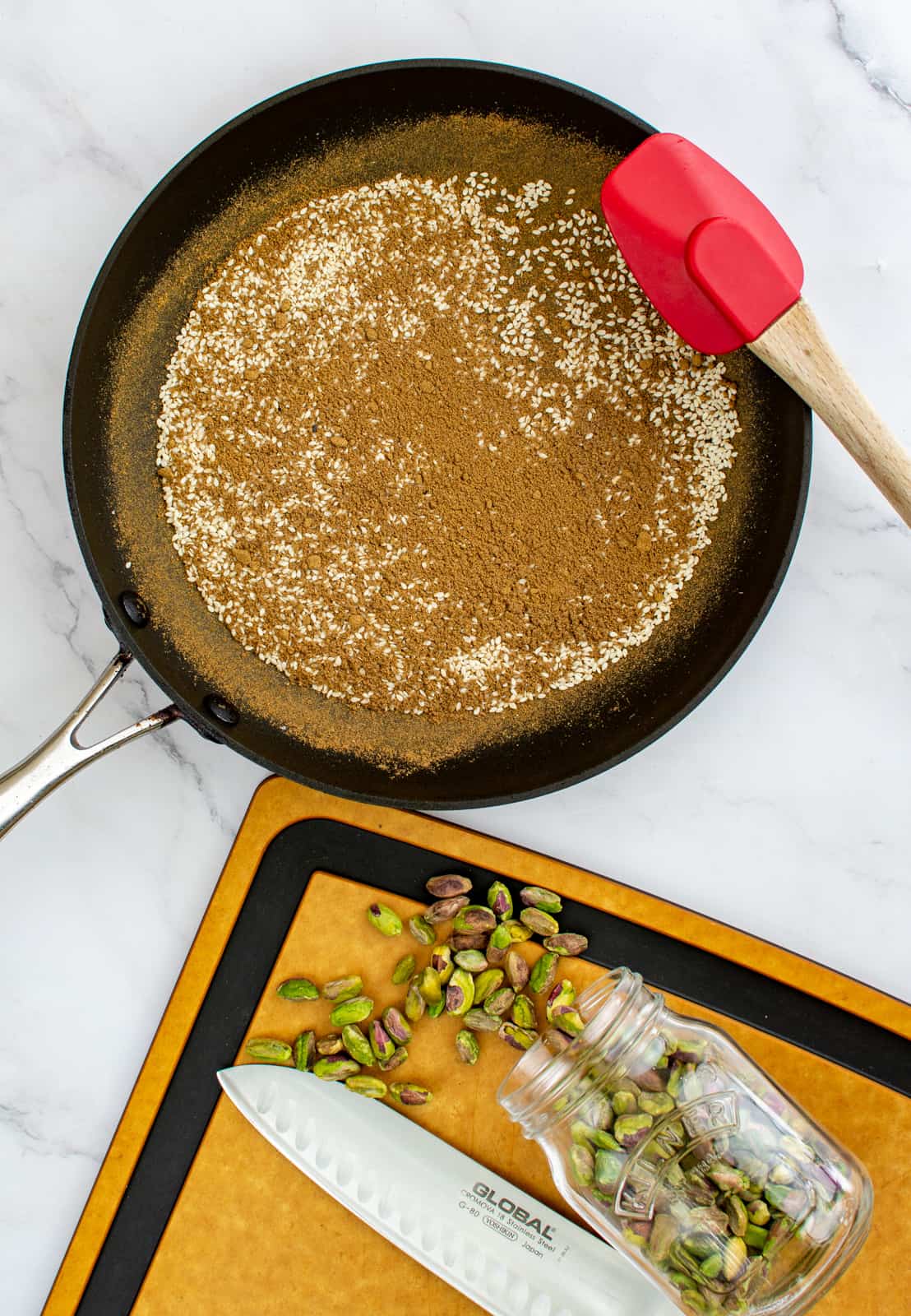 spices toasting in frying pan, pistachio on a chopping board