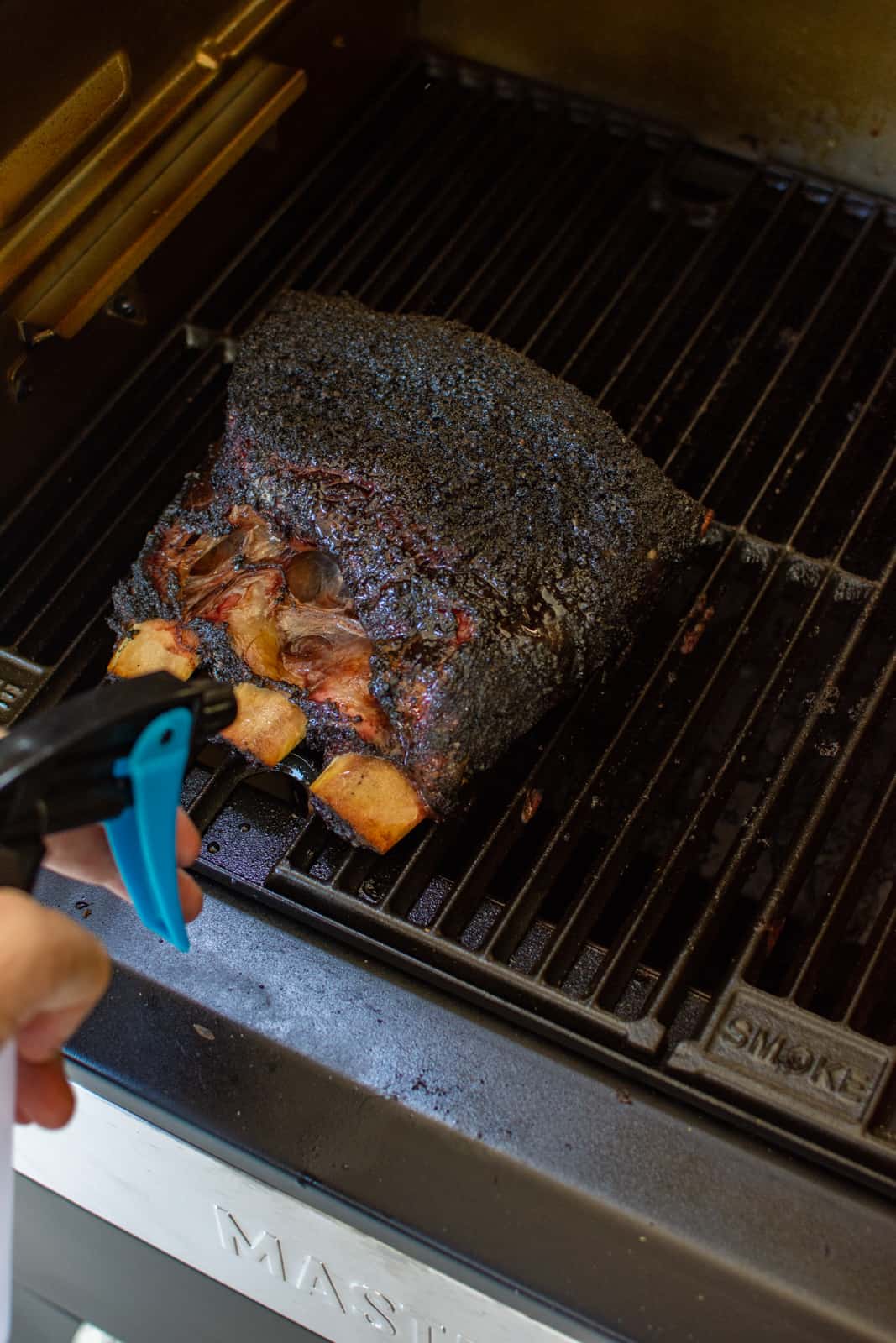 smoked short ribs getting a spritz as they smoke