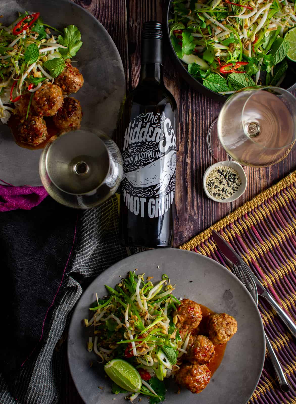 table with Asian pork meatballs, wine glasses and hidden sea pinot grigio