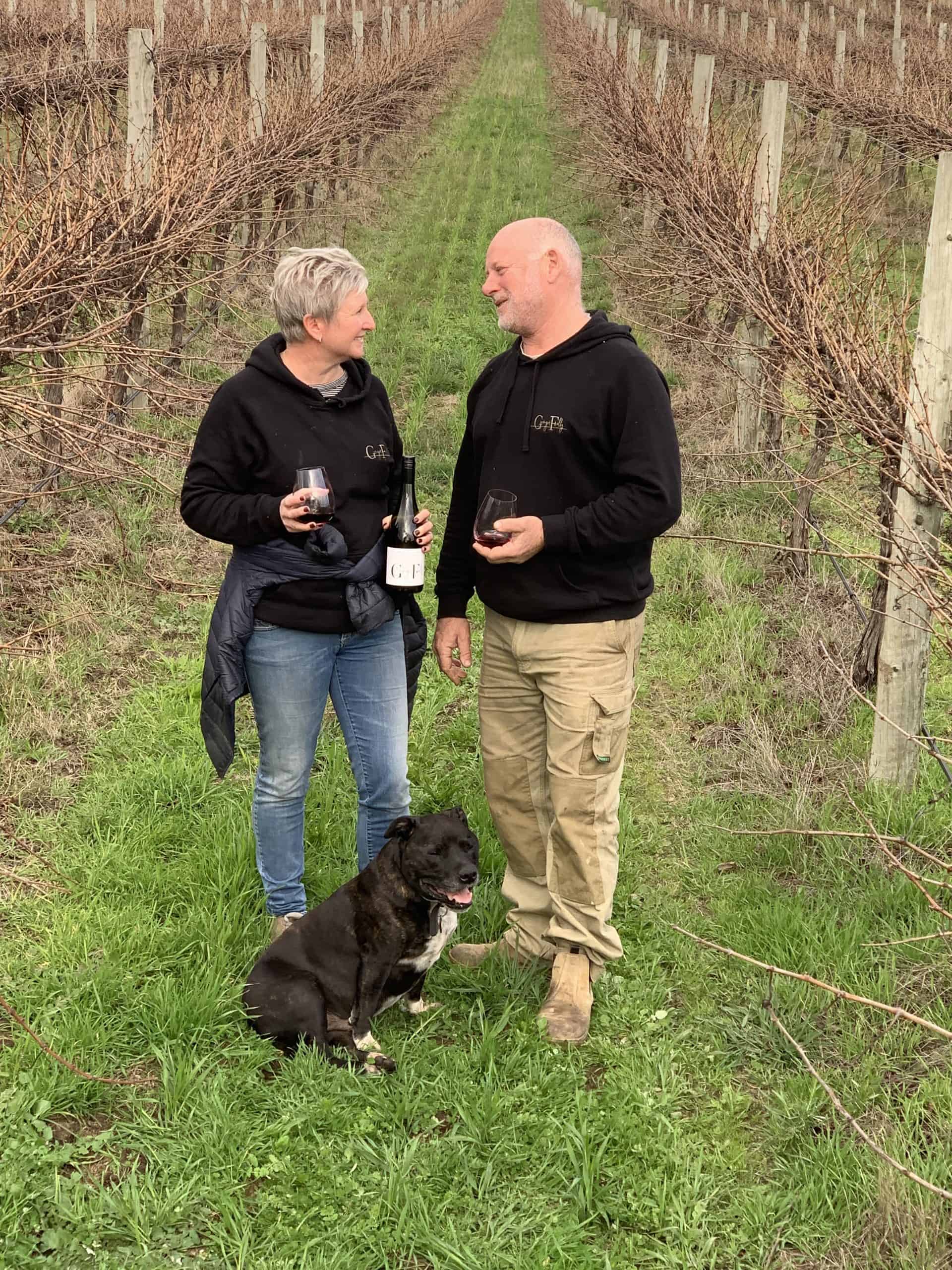two people holding wine standing in vineyard
