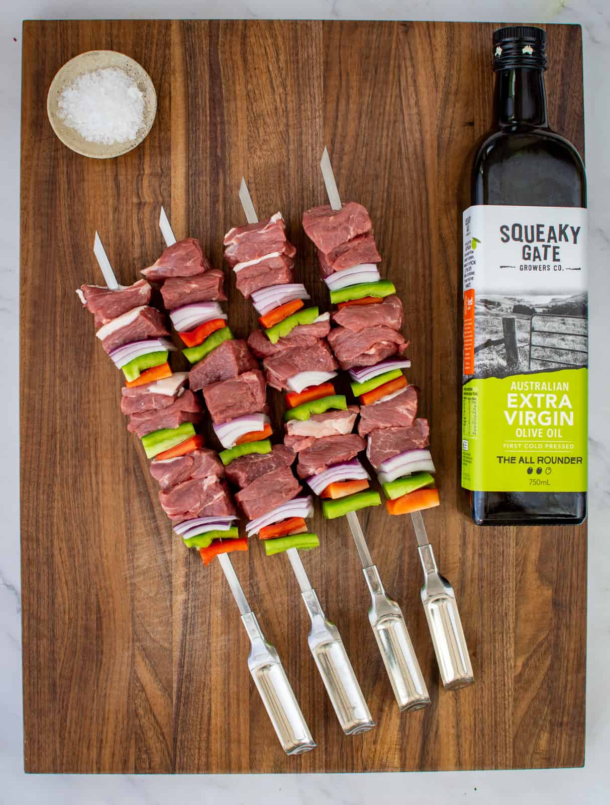 lamb and vegetable skewers on a chopping board 