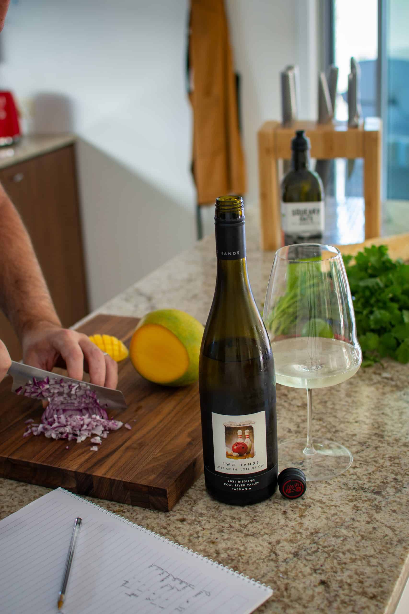 someone slicing an onion on chopping board with other food on kitchen counter top