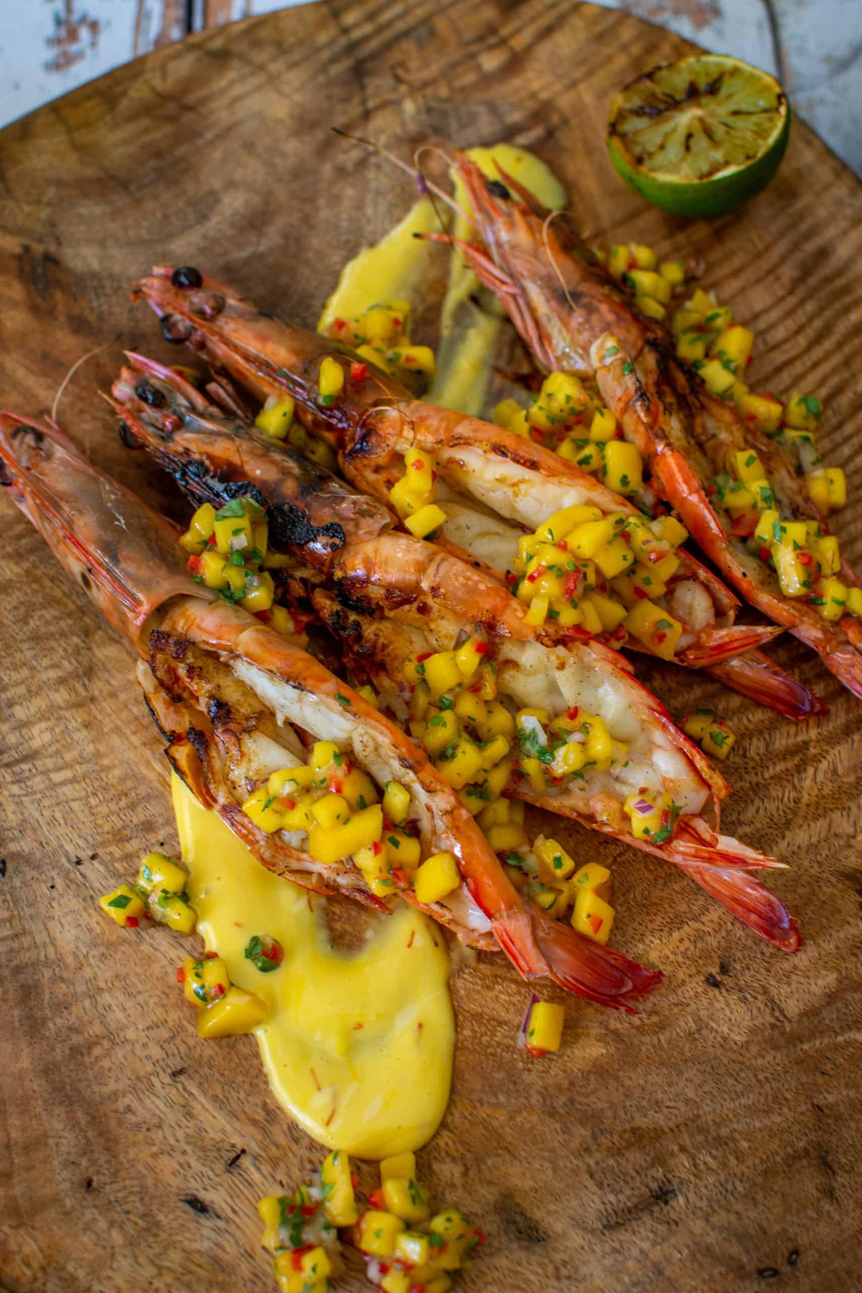 BBQ prawns on wooden chopping board with mango chilli salsa and saffron aioli