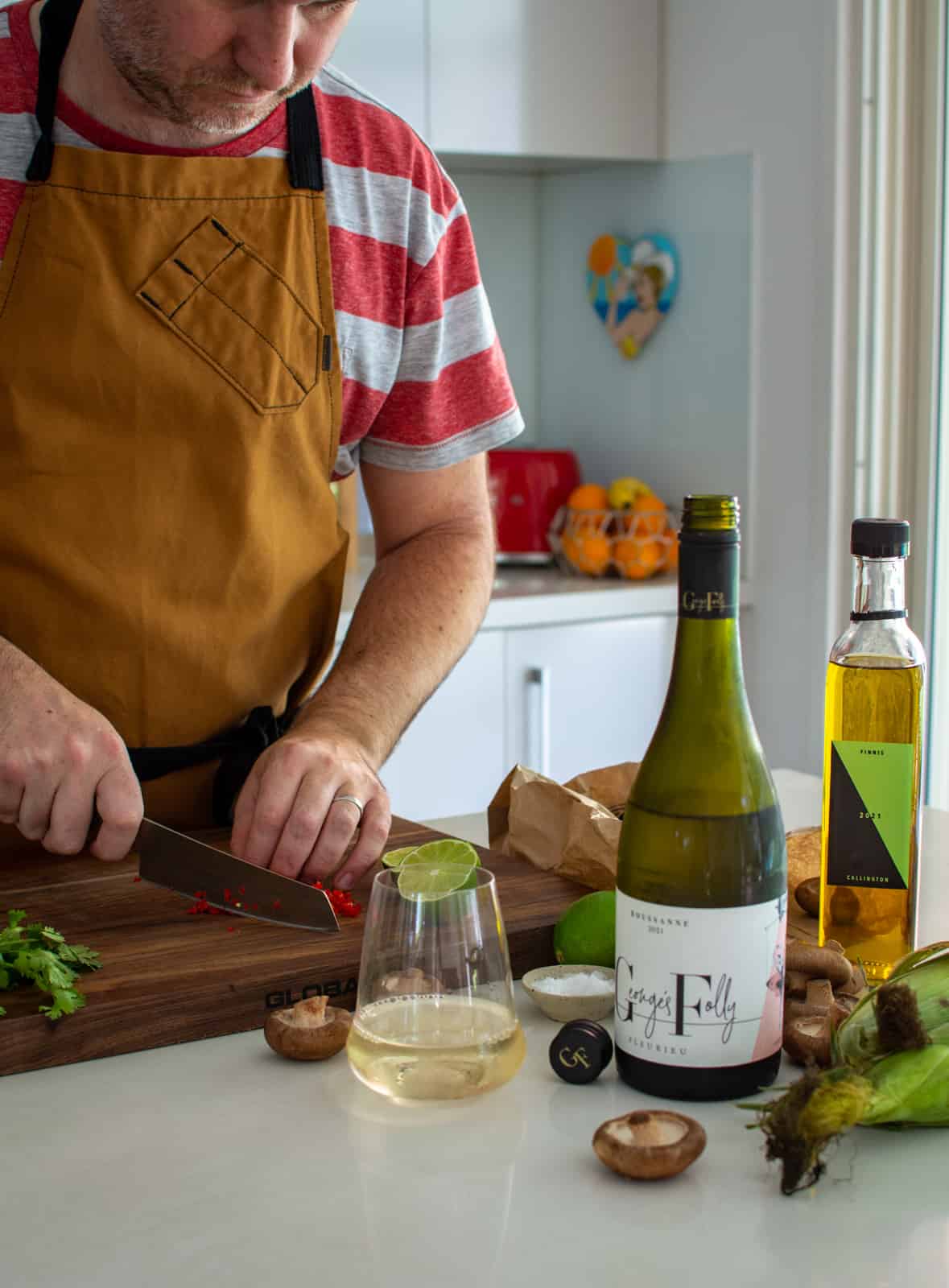 someone chopping chilli in a kitchen, white wine and multiple ingredients around them