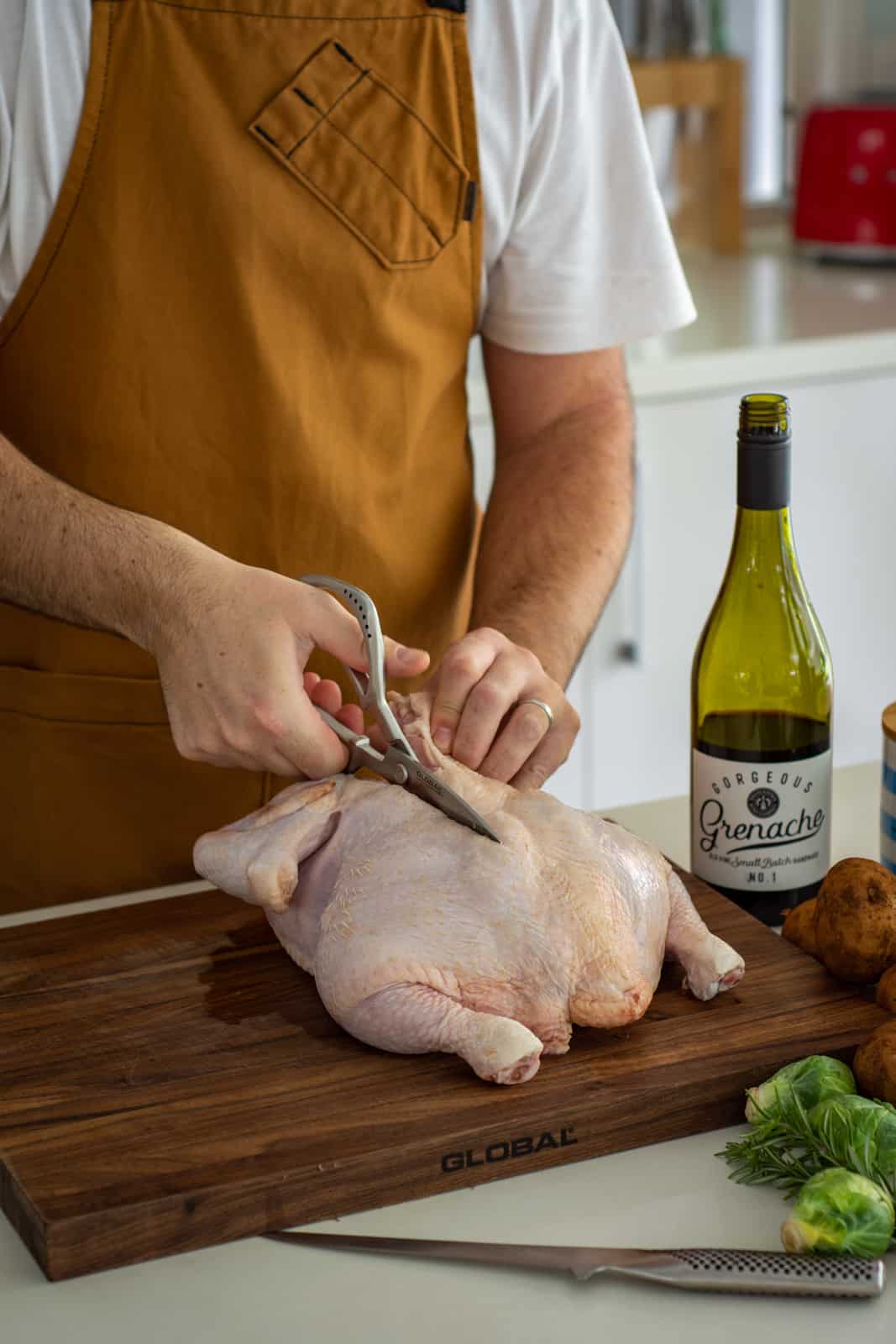 someone cutting a chicken with scissors in the kitchen