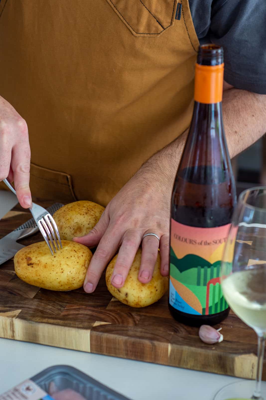 someone pricking potatoes with a fork on a chopping board