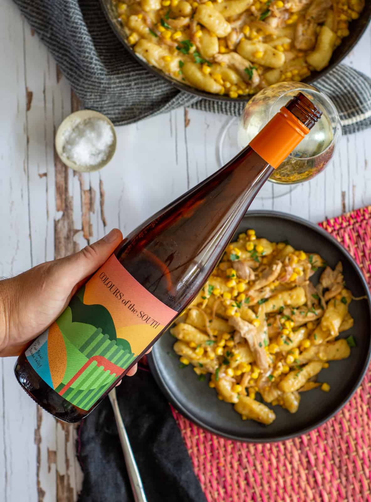 birdseye view of white wine being poured with bowls of gnocchi below