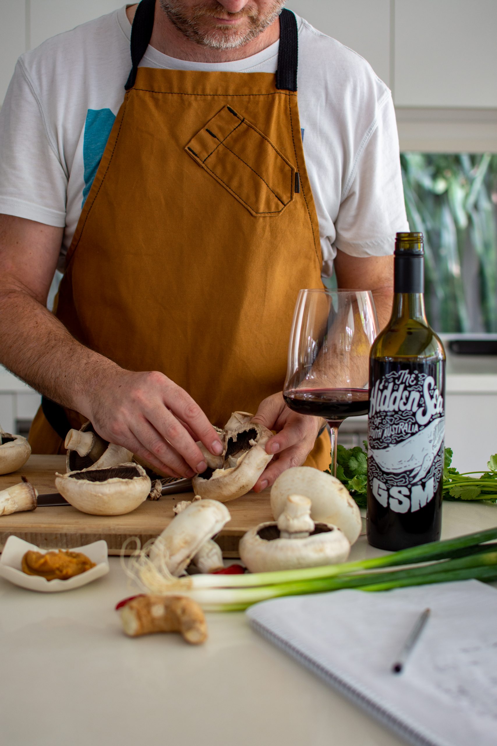 Peeling mushrooms in the kitchen with hidden sea GSM wine beside the chopping board