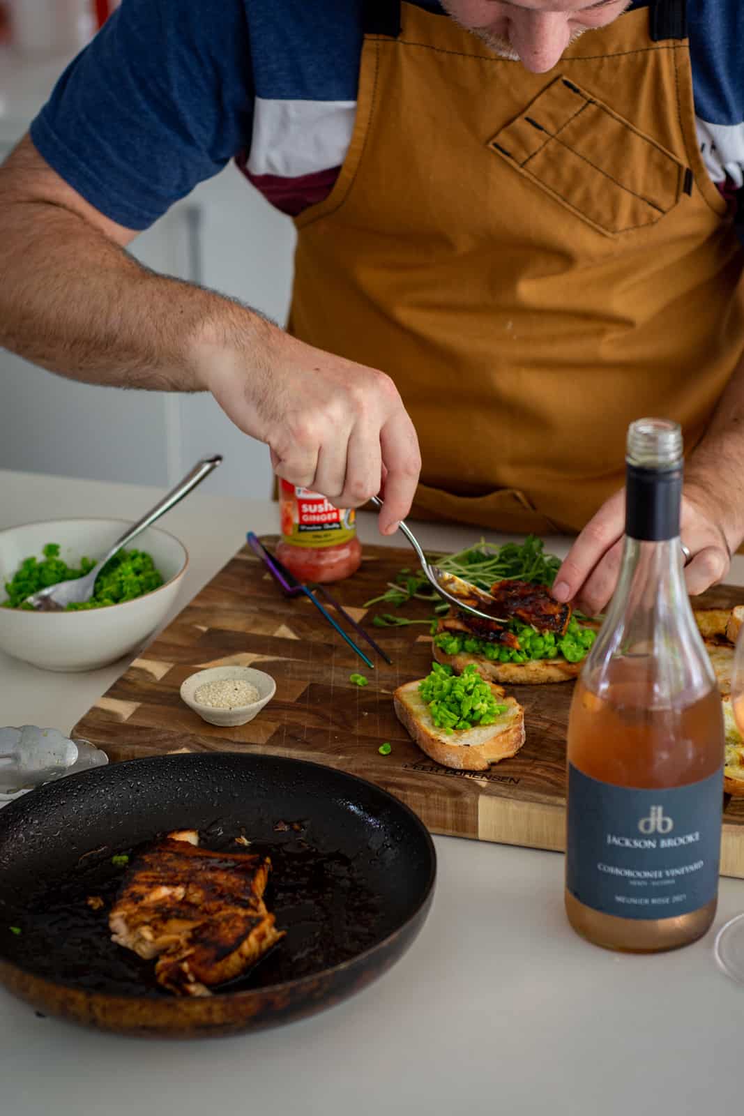 plating teriyaki salmon in the kitchen with ingredients in pan and on chopping board