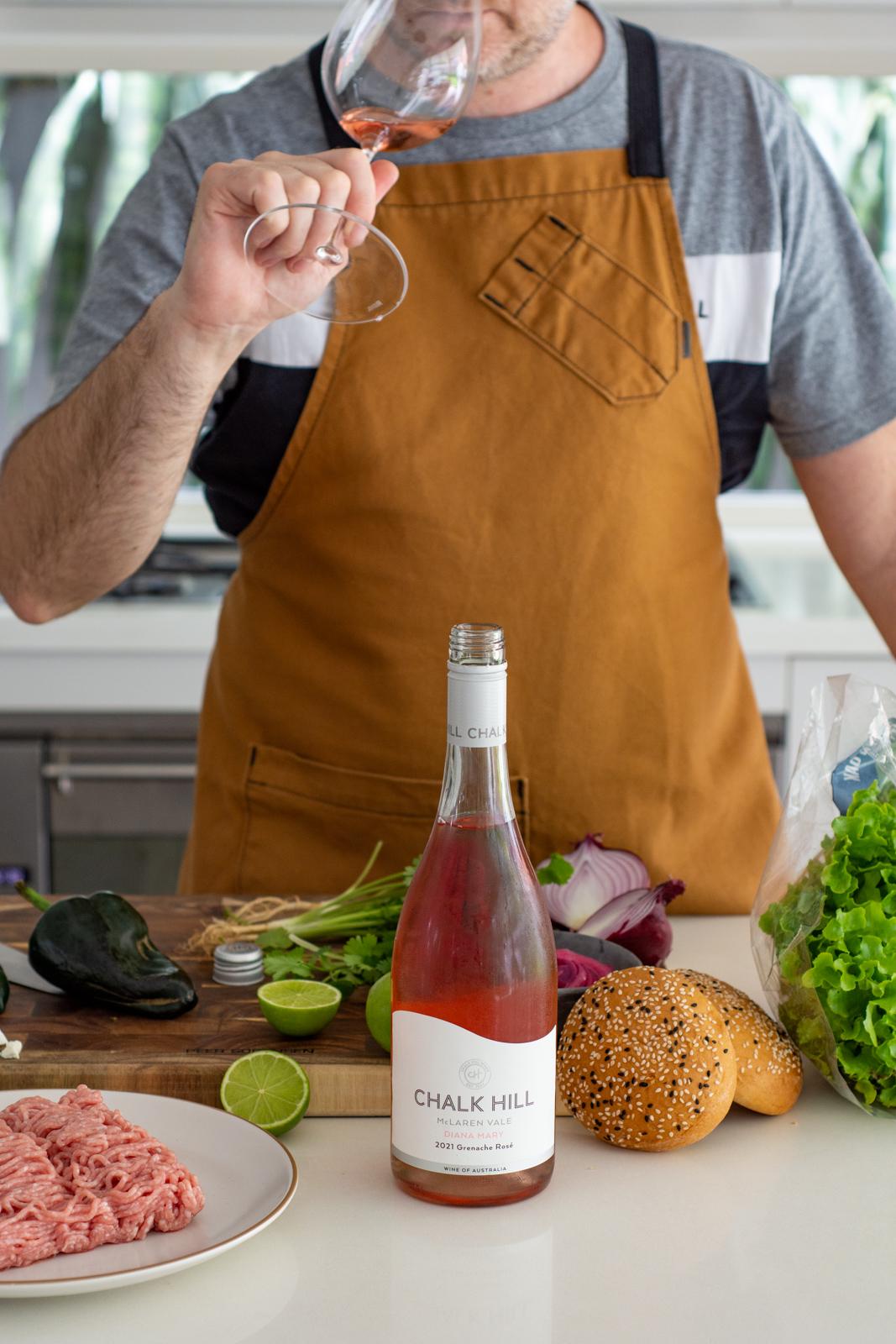 Pork burger ingredients in the kitchen with someone sipping on a glass of Chalk Hill rose wine