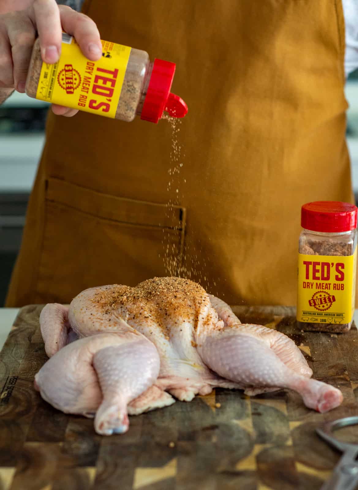 Someone drizzling Teds dry rub onto a chicken