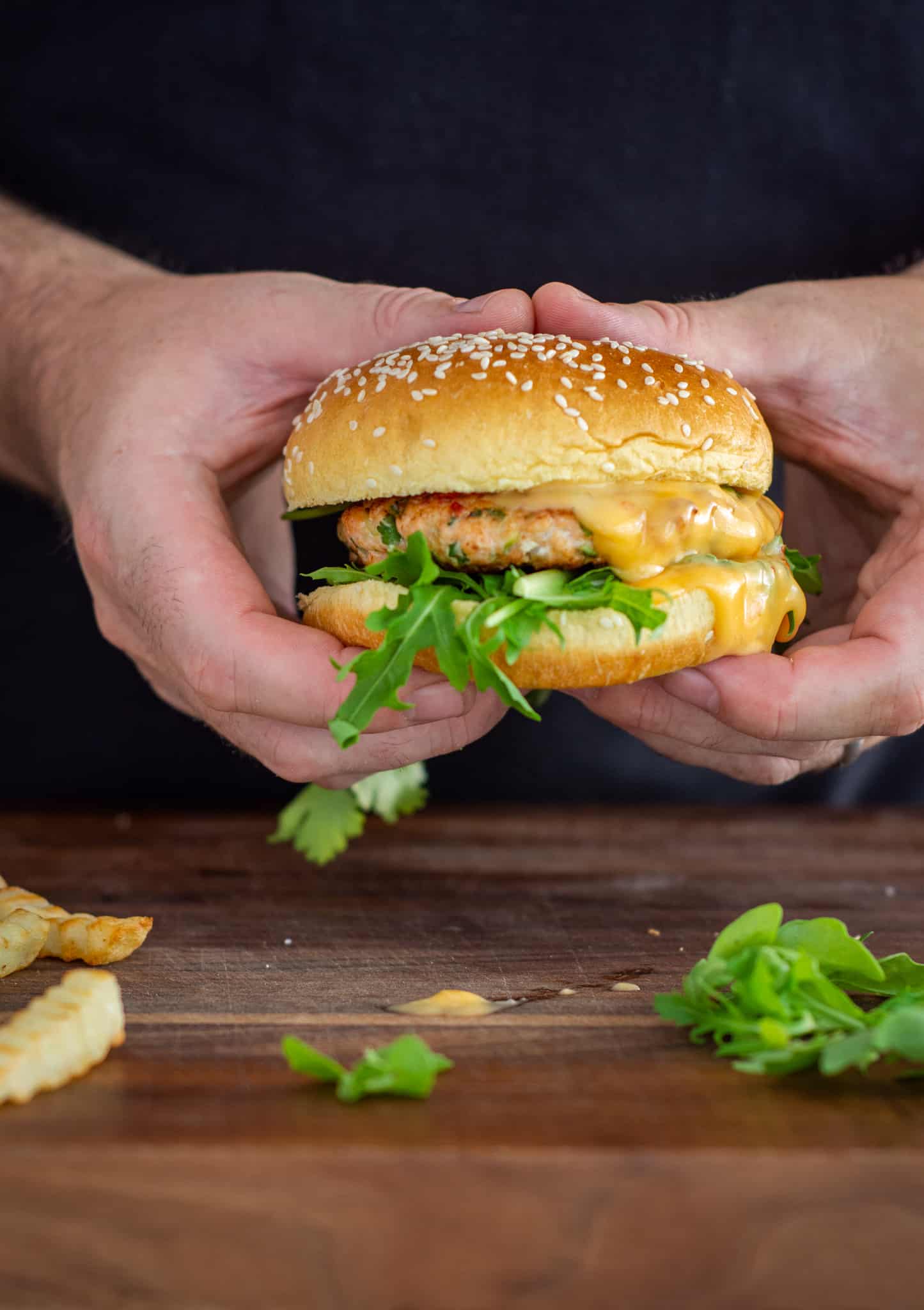 Someone holding a salmon burger in their hands