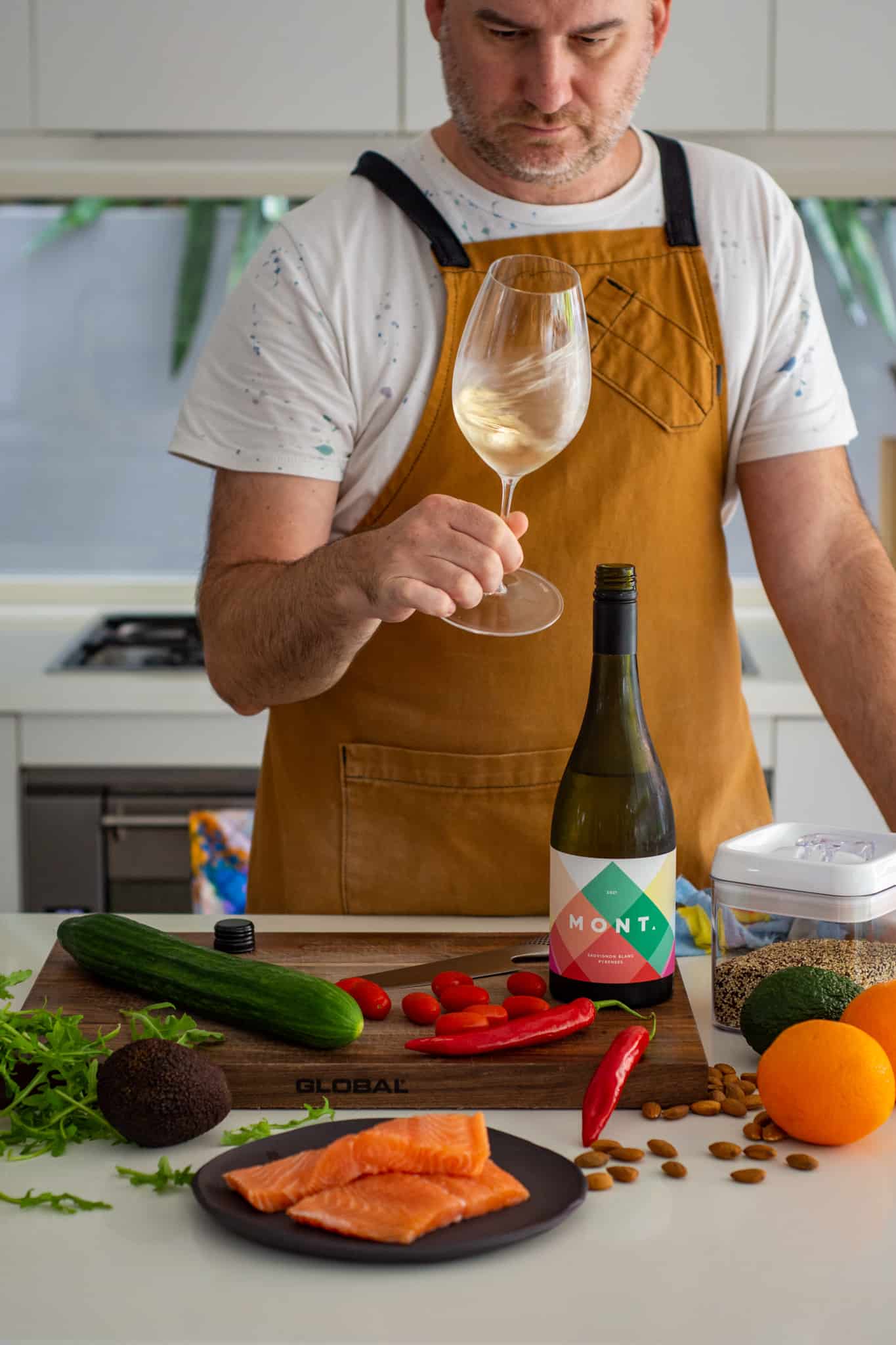 someone swirling a glass of wine in the kitchen with food on counter top