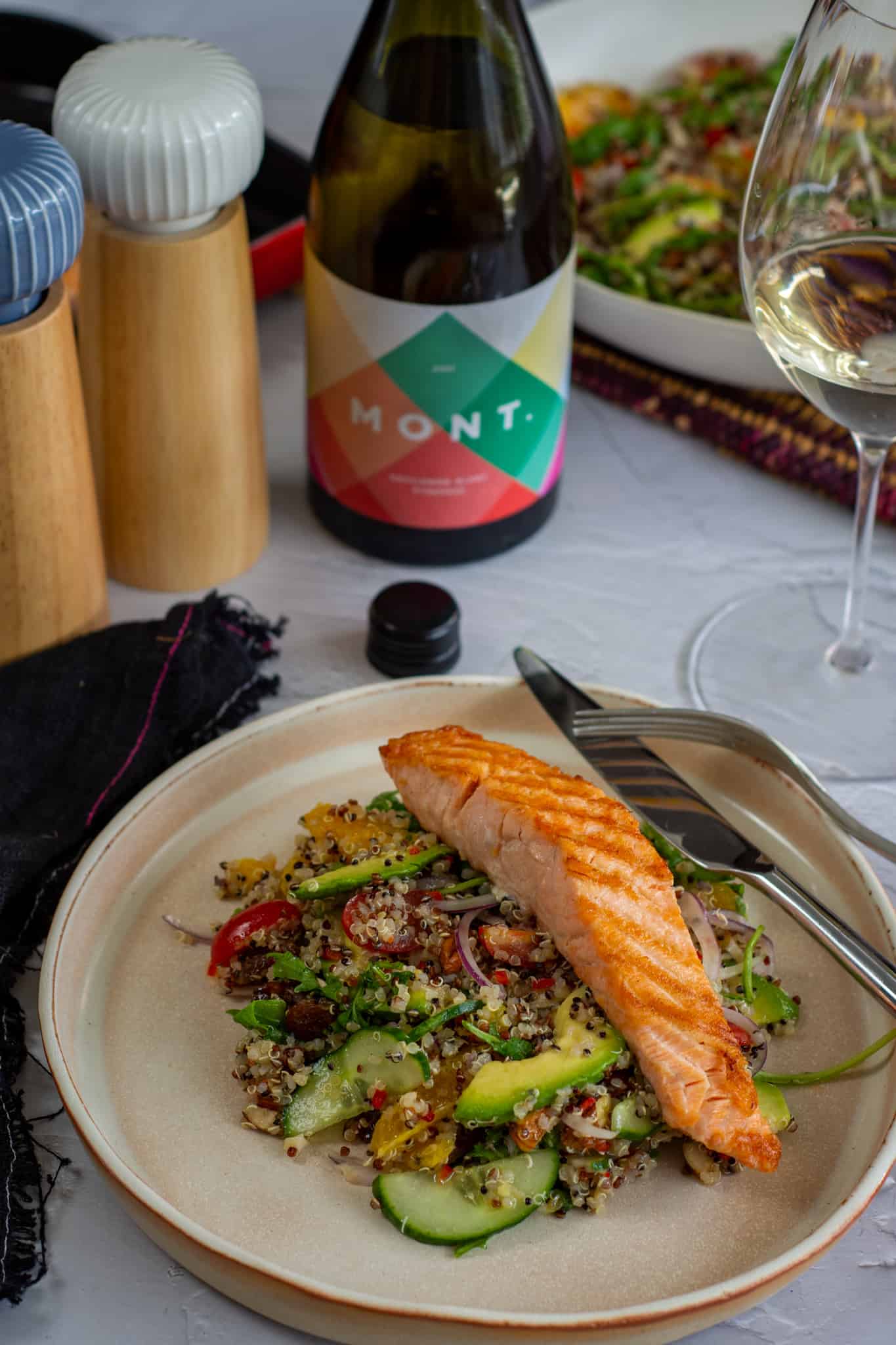 ancient grain salad with grilled salmon on a plate wit wine on table too