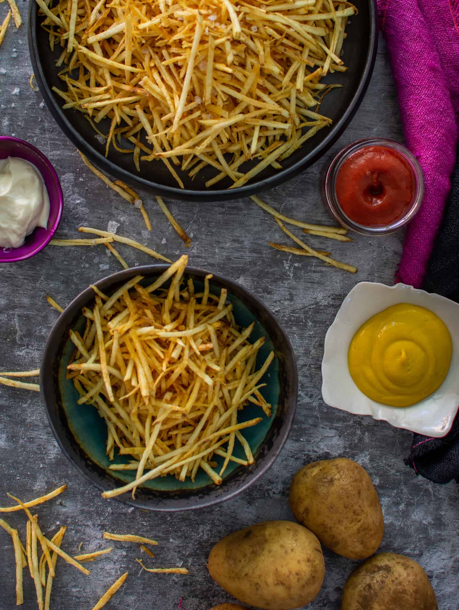 Birdseye view of bowls of shoestring fries and sauce beside the bowls