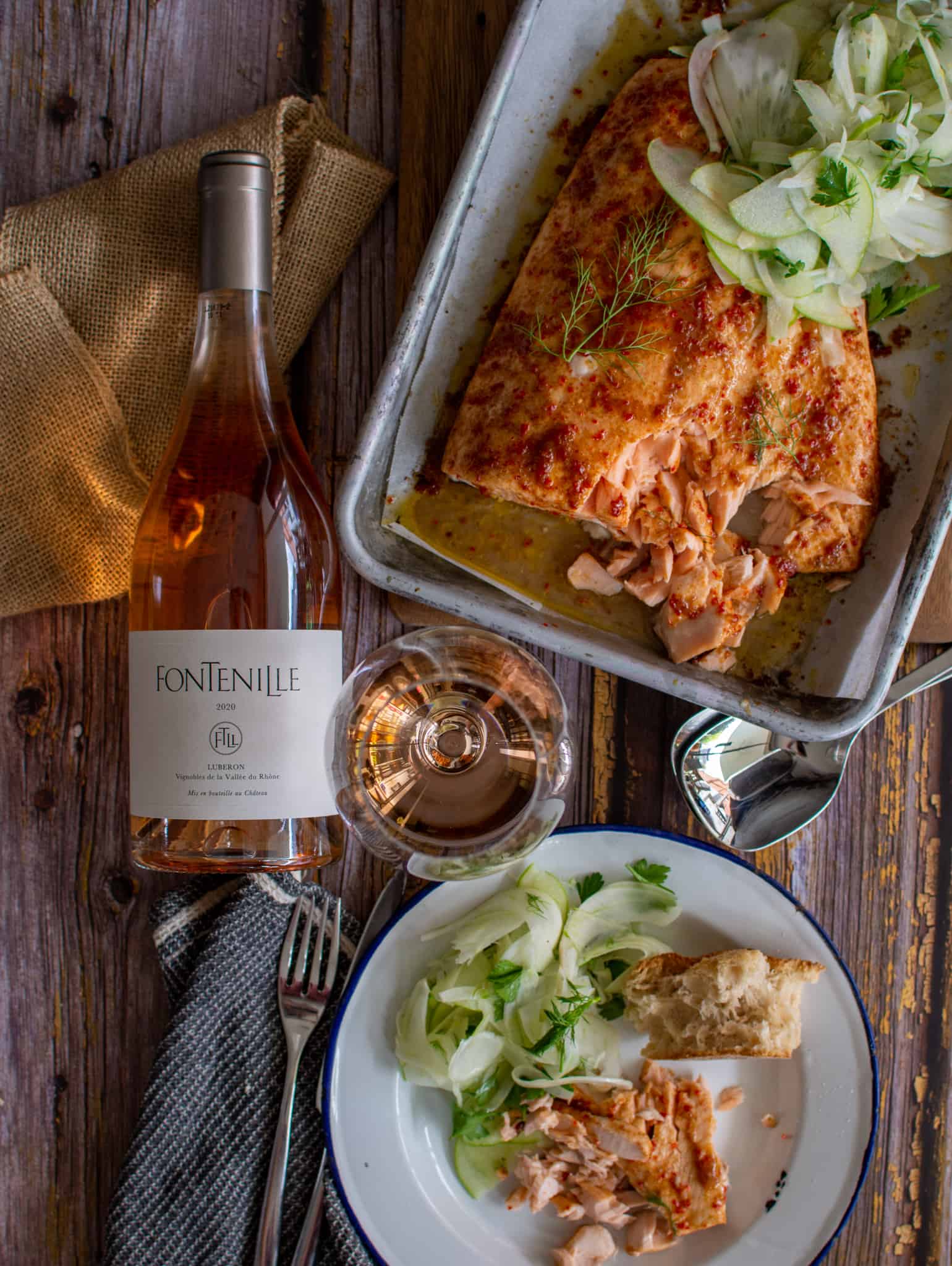 Birdseye view of table setting including maple glazed baked salmon, fontenille rose, wine glass and a plate with salmon on it