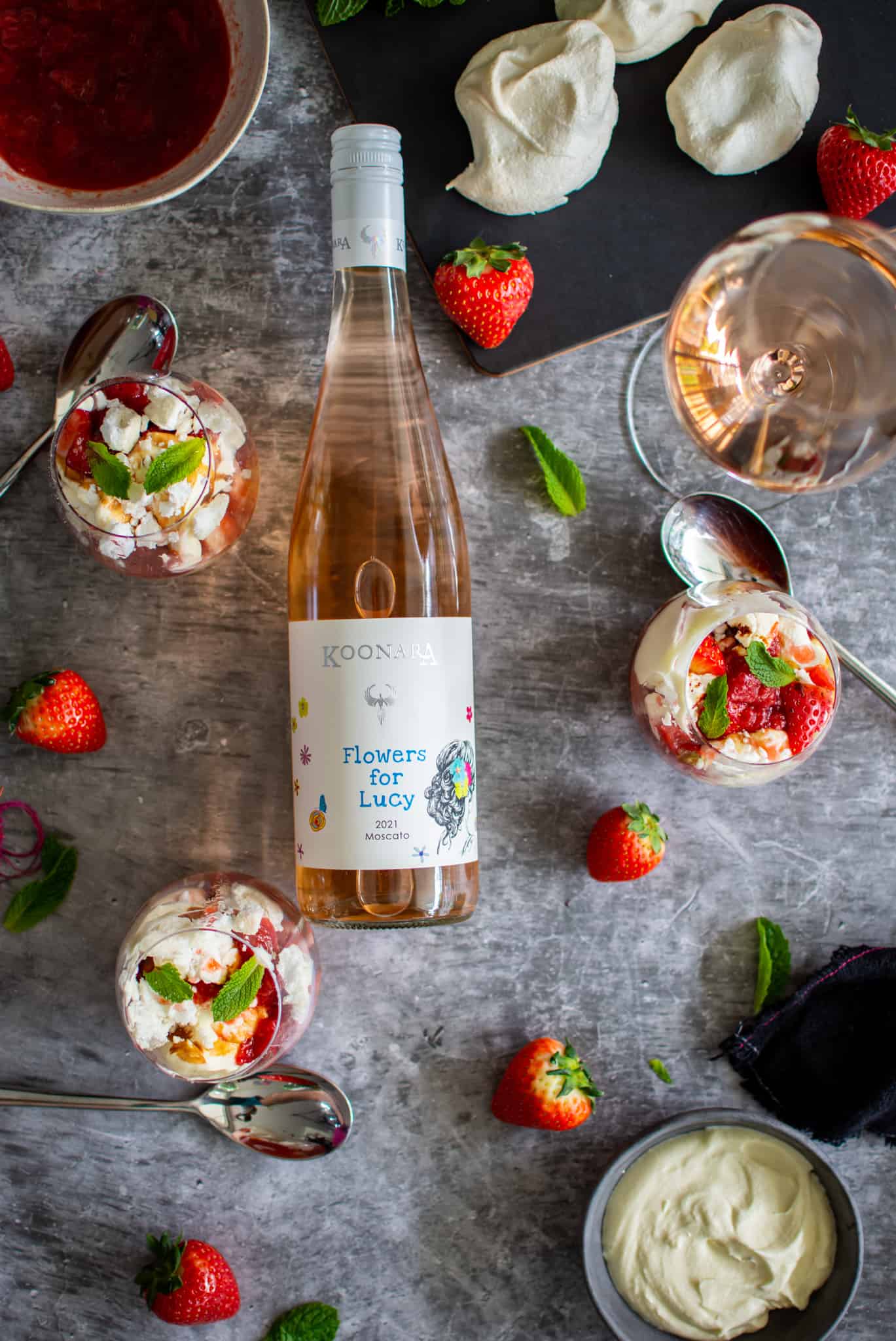 Birdseye view of Eton Mess in glasses with a bottle of Moscato and wine glasses