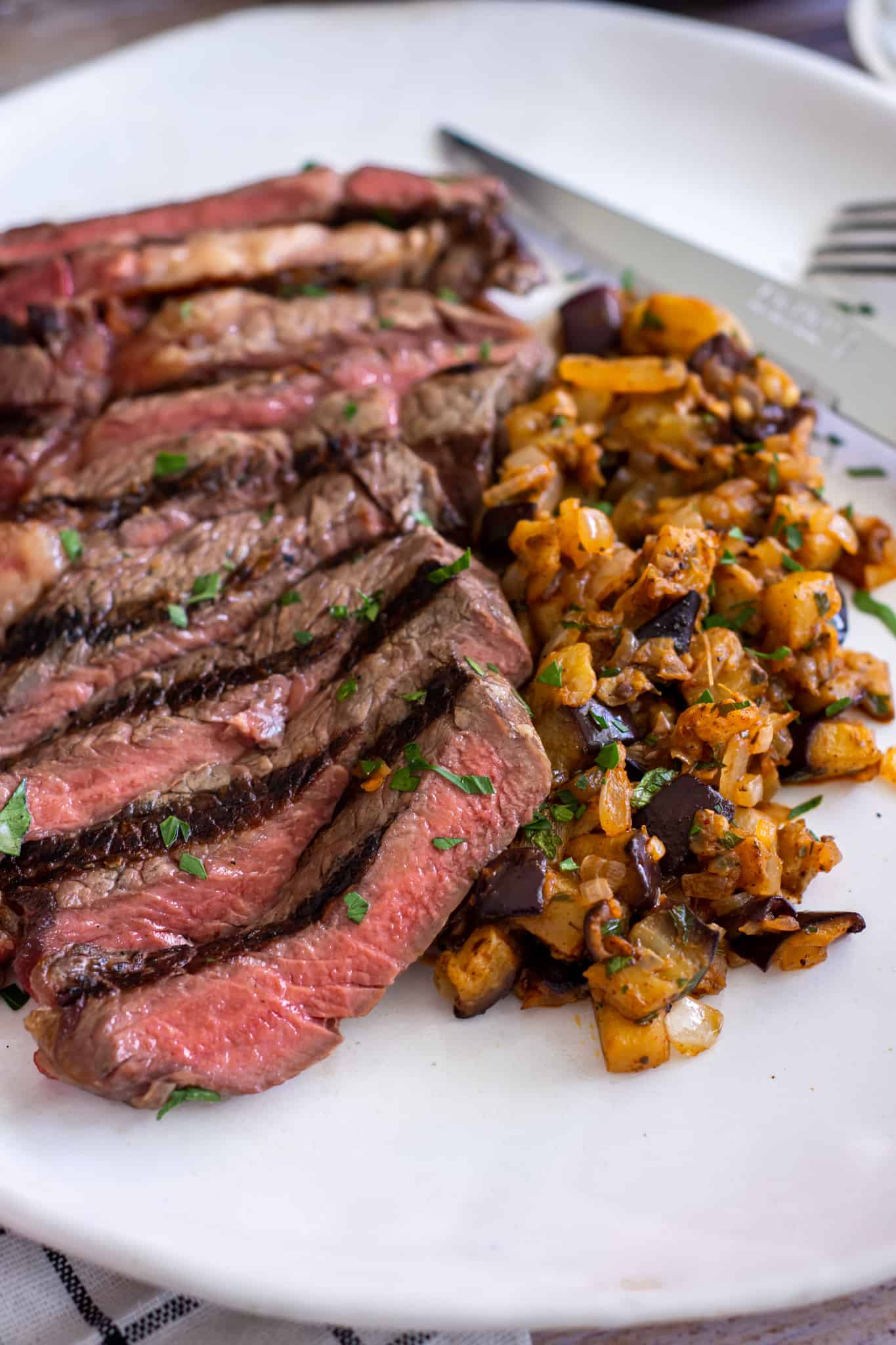 Close up of steak with spiced eggplant on a white plate