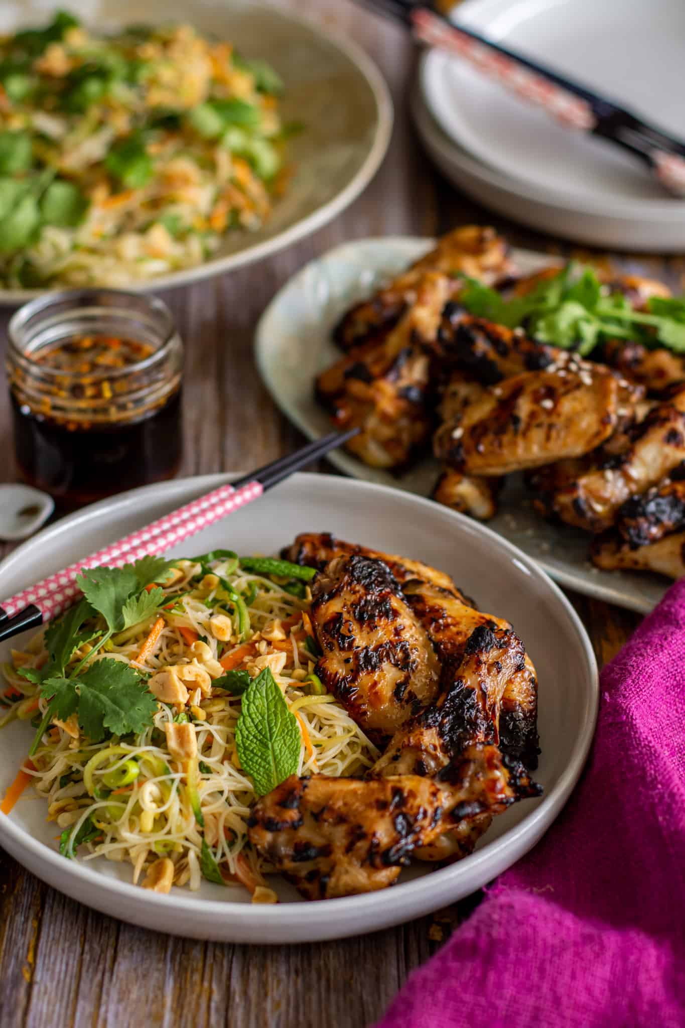 table setting with a plate of chicken vermicelli noodle salad with chicken on a plate in background