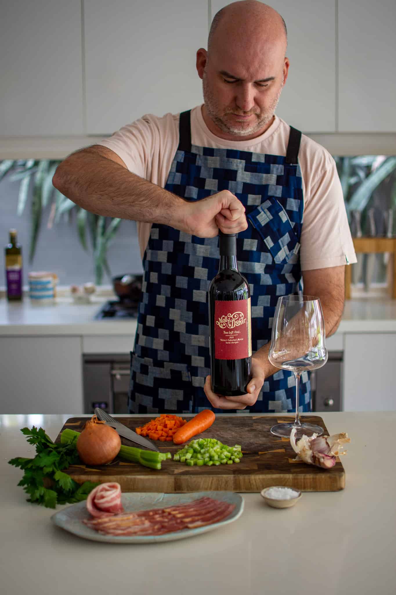 someone opening a bottle of mollydooker red wine in the kitchen with ingredients on counter top