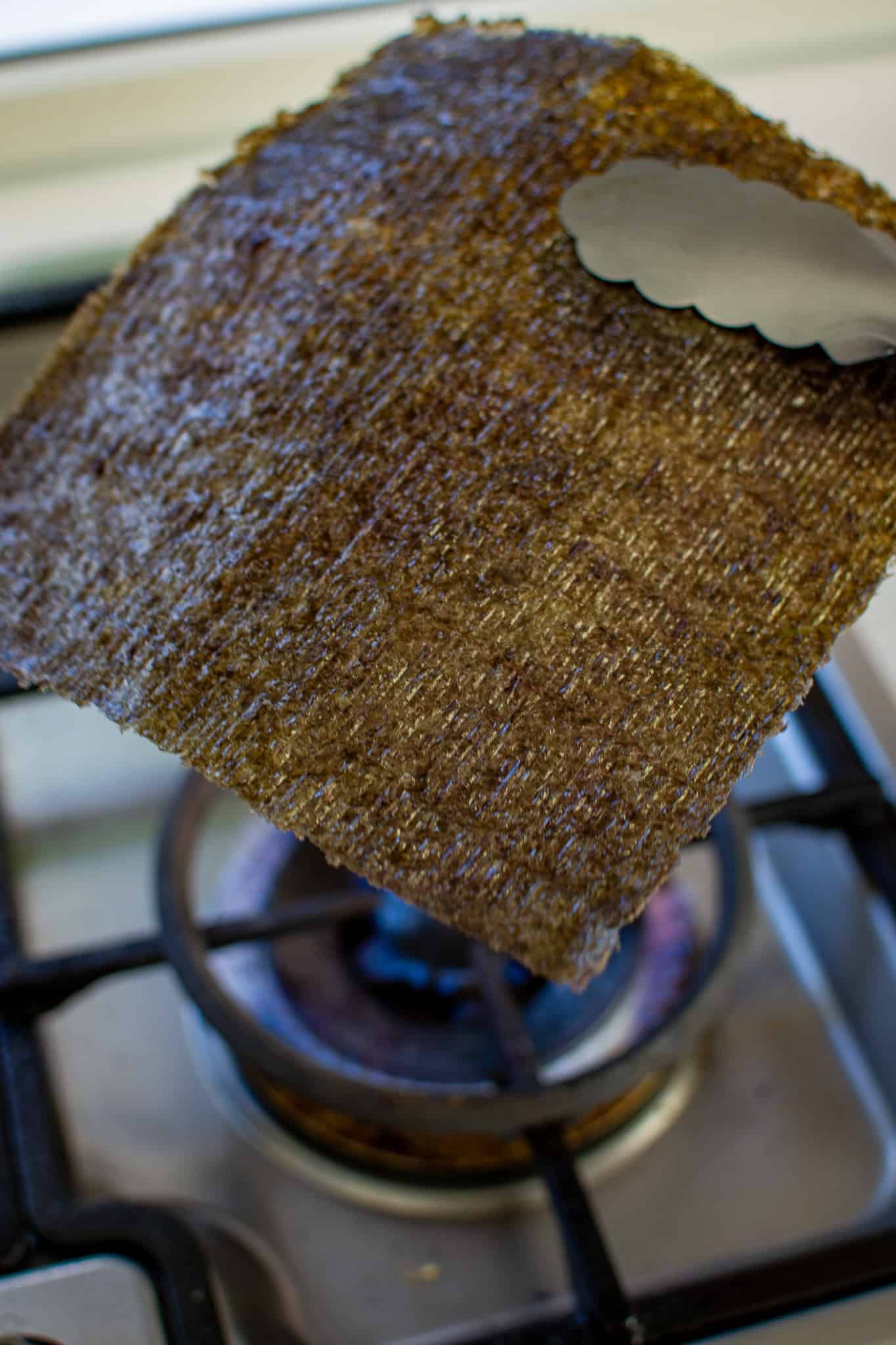toasting a sheet of nori over gas flame